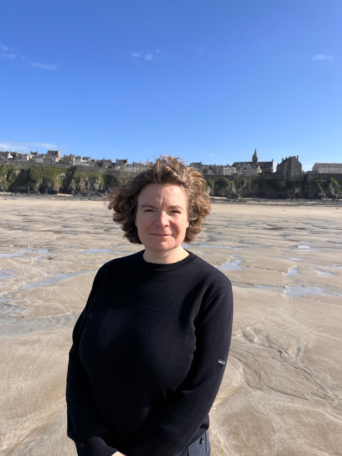 Cécile sur la plage de Granville à marée basse, la vieille ville en arrière-plan